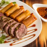 Seared beef tenderloin slices with herb crust alongside sweet potato rolls, served with dipping sauce